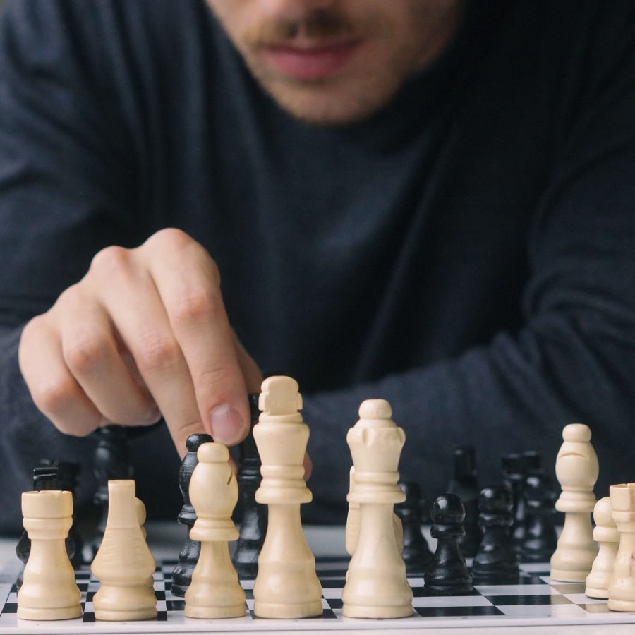 Ein Mann (Steven Ullrich), der Schach spielt und eine Figur mit seiner Hand bewegt. Online Business